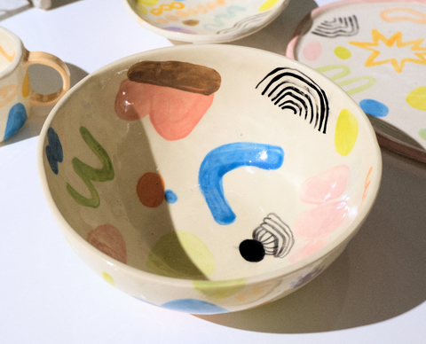 Colorful ceramic bowl with abstract designs on a light pink background